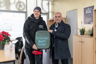zwei Männer halten einen grauen Rucksack mit Leuchtschrift "Erfurter Nachteulen"