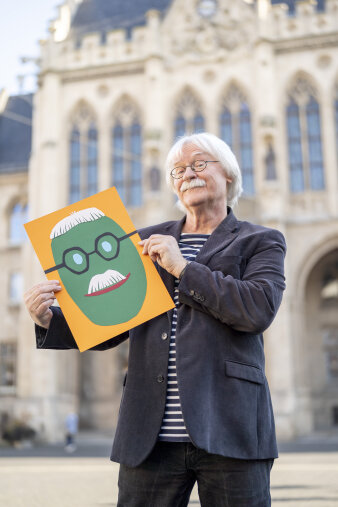 Ein älterer Mann zeigt eine mit Buntpapier gestaltete Puffbohne.
