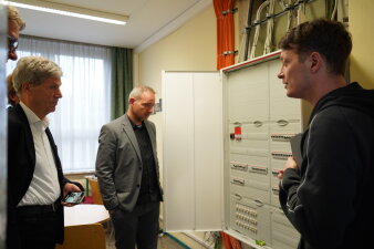 Vier Männer stehen an einem Schaltkasten und unterhalten sich.