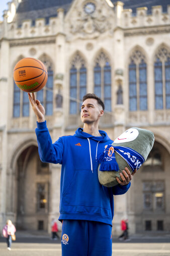 Ein Mann jongliert einen Basketball und hält eine gebastelte Puffbohne. 