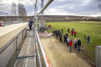 Menschen auf und vor einem Baugerüst an einem Rohbau