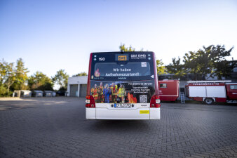Auf dem Heck eines Busses steht: „Wir haben Aufnahmezustand“. Es wird um mehr Personal für die Feuerwehr geworben. 