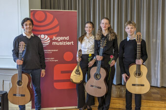 vier Jugendliche, davon drei mit Gitarre, eine mit Mandoline