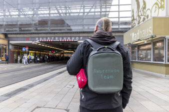 Rückansicht einer Person, die einen Rucksack mit Leuchtschrift "Awareness Team" trägt