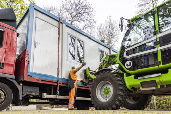 ein Container wird von einem Radlader aufgenommen