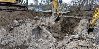 Ein Bagger zerlegt Betonteile im aufgewühlten Boden. 