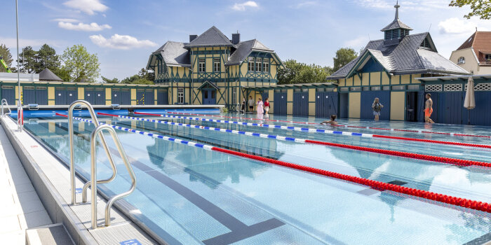ein Schwimmbecken, im Hintergrund ein Fachwerkegebäude