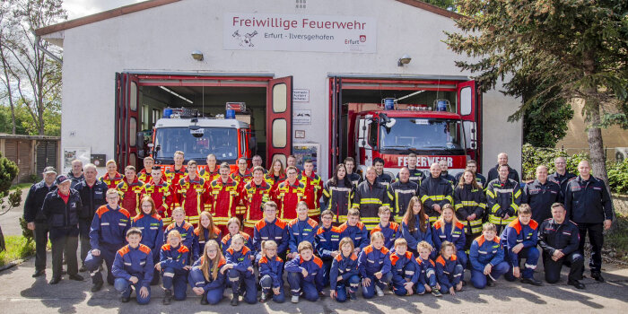 Vor einem Feuerwehrgerätehaus sind viele Erwachsene und Kinder in Feuerwehruniform zu sehen. 