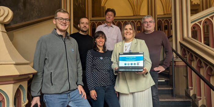 sechs Personen stehen auf den Treppen im Erfurter Rathaus, eine Frau hält einen Laptop