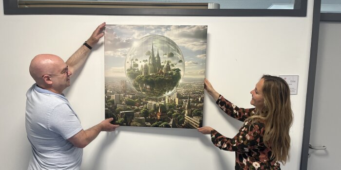 zwei Personen hängen ein Bild im Flur eines Gebäudes aus