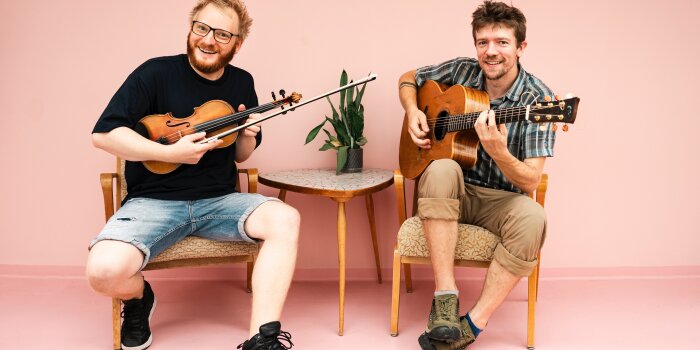 zwei Männer, einer mit Violine, einer mit Gitarre