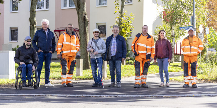acht Personen, davon drei in orangefarbener Arbeitskleidung