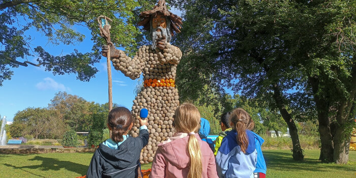 mehrere Kinder stehen vor einer Figur aus Kürbissen