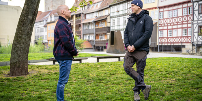 zwei Männer unterhalten sich, im Hintergrund ist die Erfurter Krämerbrücke zu sehen