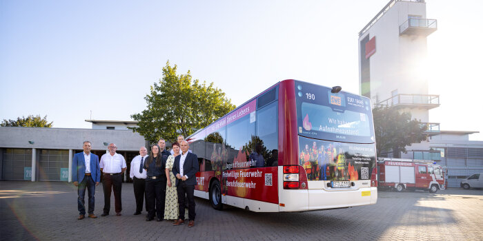 Acht Menschen stehen an einem Bus, der für die Feuerwehren in Erfurt wirbt.