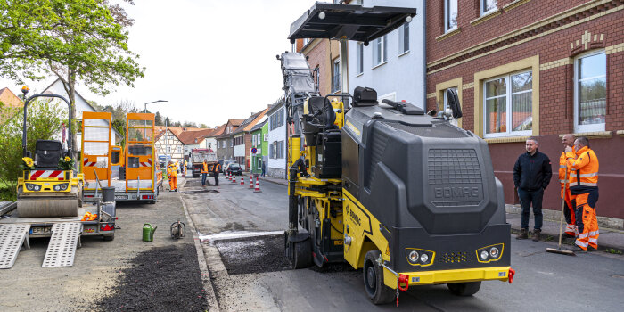 eine schwarz-gelbe Maschine bearbeitet eine Fläche im Asphalt