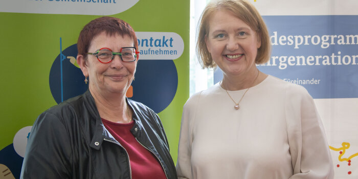 Zwei Frauen in Porträtaufnahme. Sie stehen lächelnd nebeneinander.