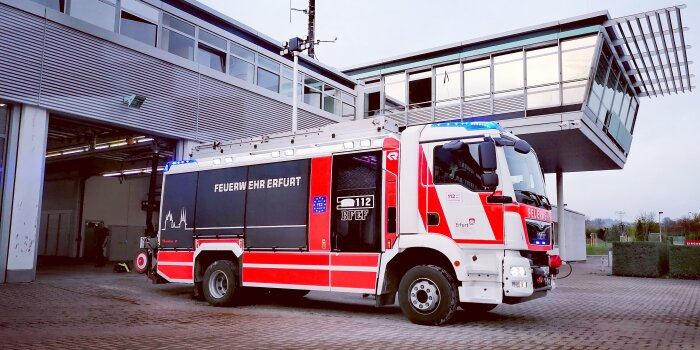 Ein Löschfahrzeug der Feuerwehr Erfurt steht vor einer Halle.