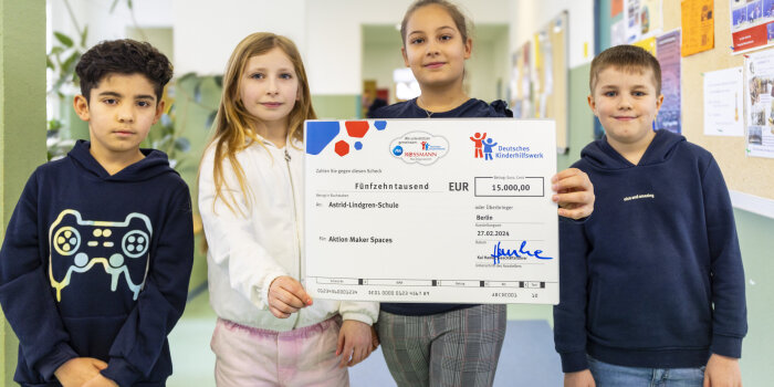Eine Gruppe aus vier Kindern zeigt einen Scheck. Darauf steht: 15.000 Euro für die Astrid-Lindgren-Grundschule.