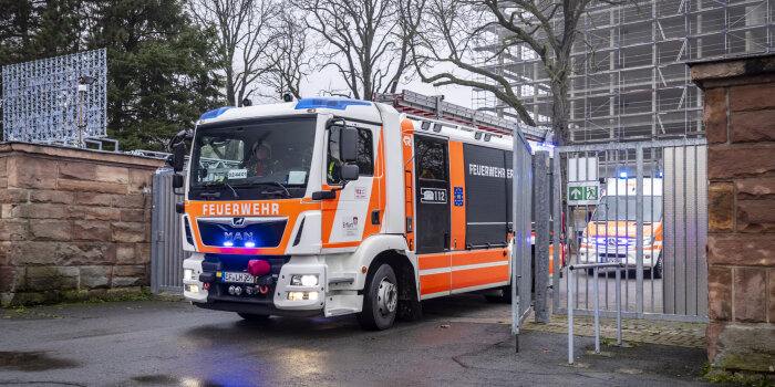 Ein Feuerwehrfahrzeug passiert ein eisernes Tor.