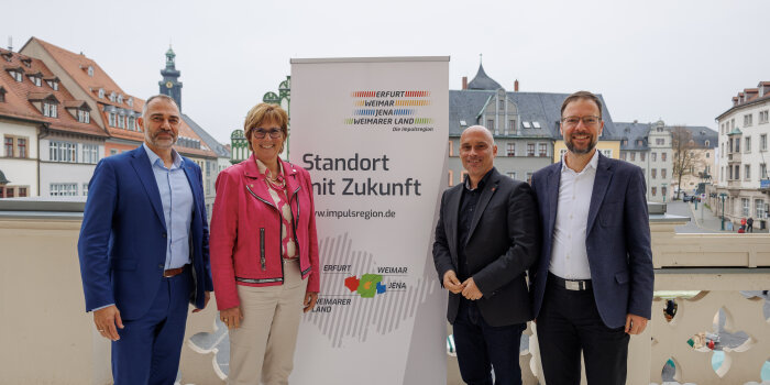 drei Männer und eine Frau stehen neben einem Roll-up mit Aufdruck "Standort mit Zukunft"