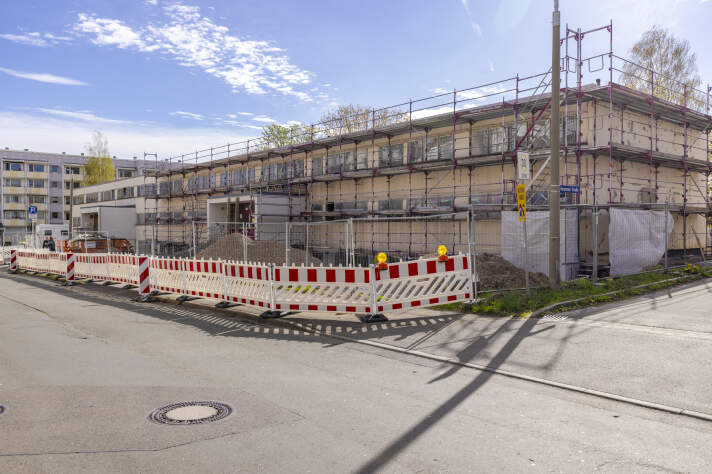 Ein zweistöckiges Gebäude ist eingerüstet. Davor stehen auch Warnbaken.