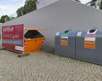 ein orangefarbener Müllcontainer, daneben stehen zwei Glascontainer