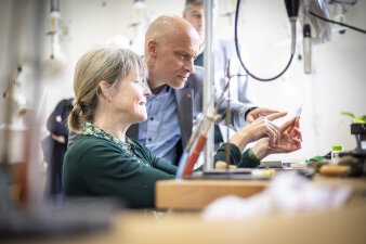 eine Frau und ein Mann betrachten gemeinsam ein filigranes Werkstück an einer Werkbank