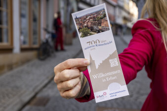 eine Hand hält einen länglichen Aufkleber mit Krämerbrücken-Foto und Schriftzug "700 Jahre steinerne Krämerbrücke"