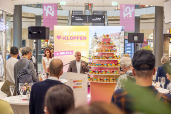 ein Mann steht an einem Pult und spricht vor Publikum