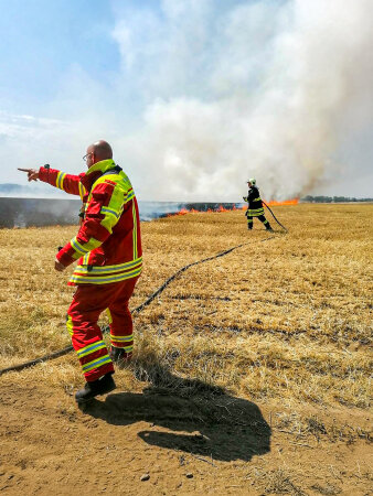 zwei Feuerwehrmänner beim Löschen eines Feldbrandes