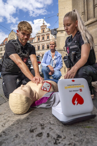 zwei Personen in schwarzer Kleidung führen Wiederbelebungsmaßnahmen an einer lebensgroßen Puppe durch