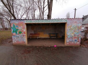 Ein verwittertes Buswartehäuschen ist voll mit Graffitti. 