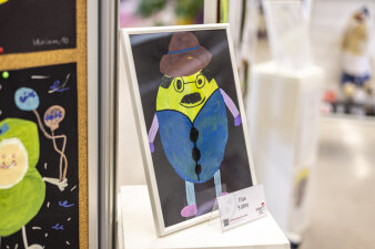 Auf einem Podest steht eine Puffbohne mit Hut, Bart und blauen Sachen. 