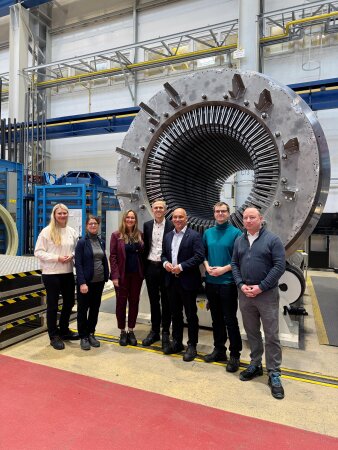 sieben Personen stehen vor einer großen Turbine
