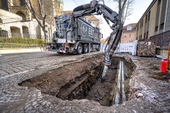 Ein großes fahrzeug mit Saugarm saugt eine Baugrube aus