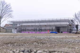 Ein zweistöckiger Neubau ist eingerüstet. Davor ist freie Fläche. 