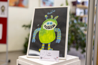 Auf einem Podest steht eine Monster-Puffbohne. Auf dem Bild steht auch das Wort: Hallo. 