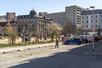 ein Spielplatz, daneben eine Straße, an der Autos parken