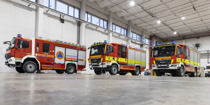Foto: Übergabe Fahrzeughalle und Fahrzeuge an Feuerwehr Erfurt © Stadtverwaltung Erfurt Drei neue Feuerwehrfahrzeuge stehen in einer großen Halle.