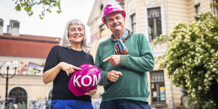 eine Frau und ein Mann, er trägt, sie hält einen pinken Bauhelm