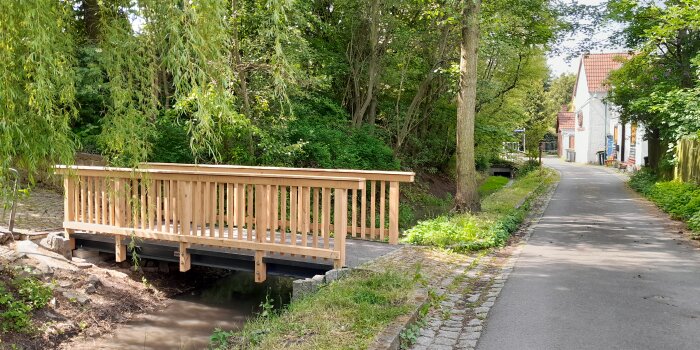 Eine Holzbrücke über einem schmalen Flusslauf innerhalb eines ortskerns