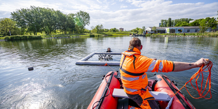 Ein Mann in einem Gummiboot auf einem See, ein weiterer Mann im Wasser positioniert eine Metallkonstruktion