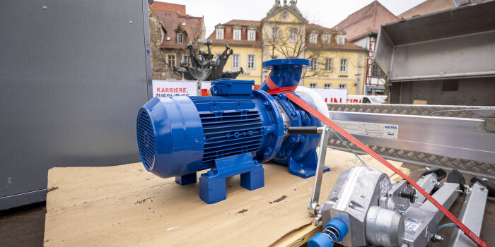 Eine blaue Pumpe, mit Spanngurten auf einem Transporter befestigt