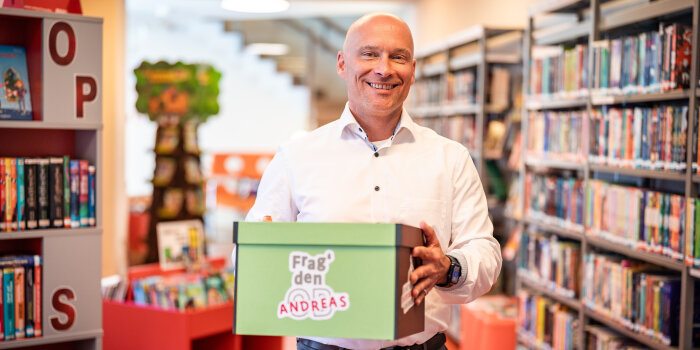 Foto: Frag den Andreas! – Was wollen Kinder vom Oberbürgermeister wissen? © Stadtverwaltung Erfurt Ein Mann mit Hemd hält eine Kiste in der Hand