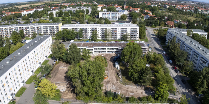 Luftaufnahme einer Grünfläche umgeben von Plattenbauten