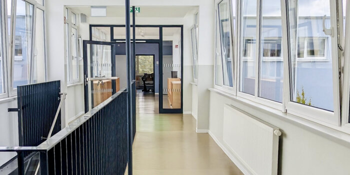 Flur eines Schulgebäudes mit Treppe und Fensterfront