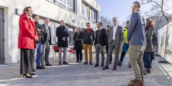 mehr als zehn Personen stehen neben einem Gebäude im Halbkreis