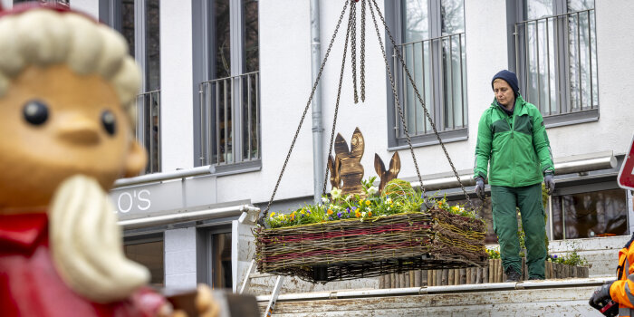 ein kleines Blumenbeet mit Osterdeko wird an einem Haken vom einem LKW gehoben