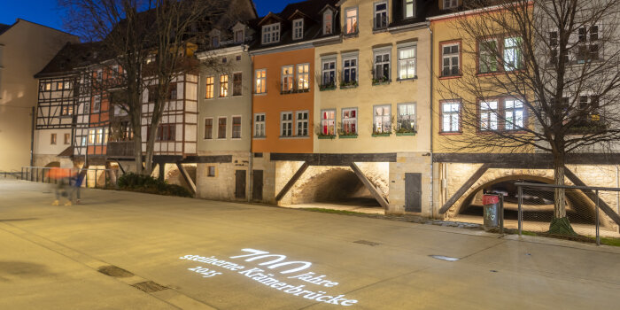 Fachwerkgebäude der Erfurter Krämerbrücke mit Lichtprojektion auf dem Boden "700 Jahre Krämerbrücke"